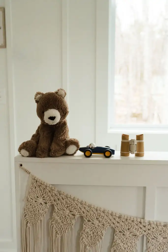 A trio of toddler toys - a stuffed teddy bear, a blue and yellow race car, and some ochre colored binoculars 