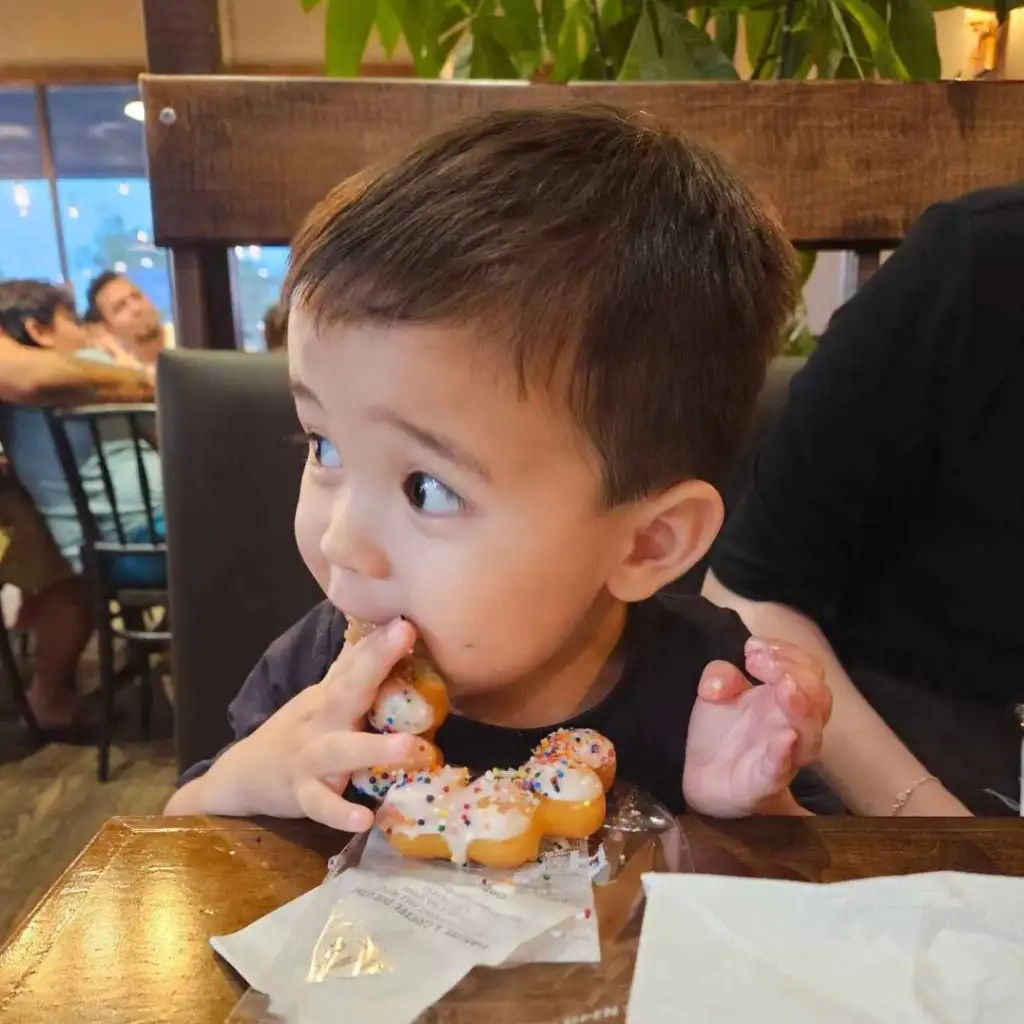 William, a toddler, enjoying a mochi donut at a Korean bakery